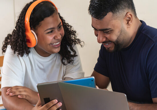 Girl in headphones with dad working on school